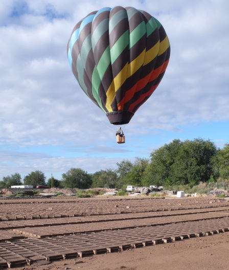 A brilliant hot air balloon low over the field